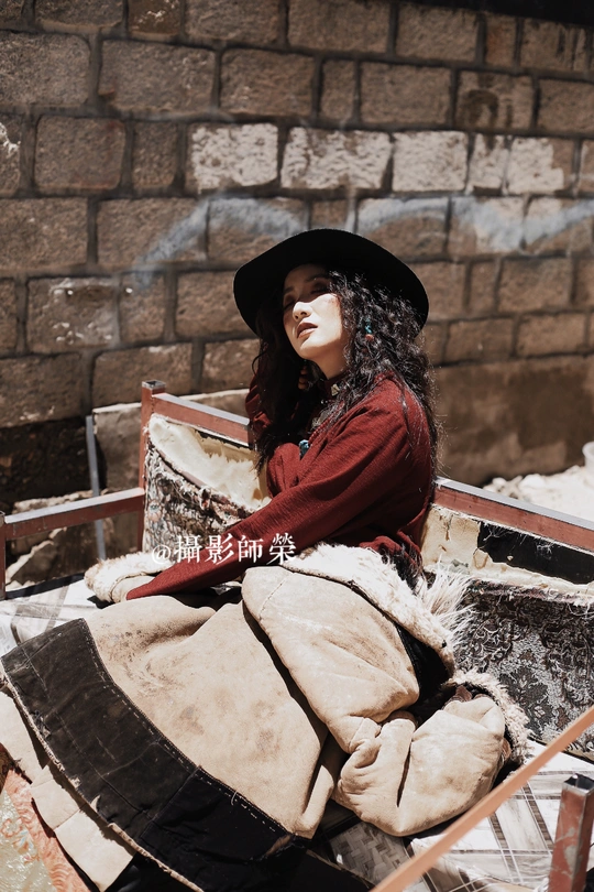 一个戴黑色帽子的年轻女子坐在雪地上的长凳上 旁边是一辆手推车。