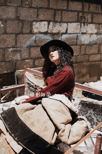 一个戴黑色帽子的年轻女子坐在雪地上的长凳上 旁边是一辆手推车。