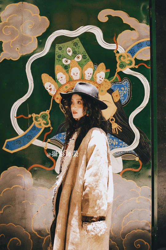 一位穿着外套和帽子站在壁画前的女人