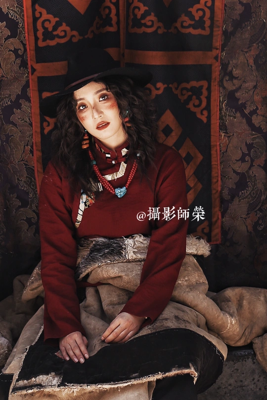 一个戴黑色帽子坐在充气玩具旁边的小女孩