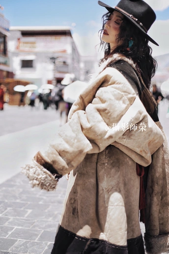 一位穿着皮草大衣和黑色帽子正在街上走的女人