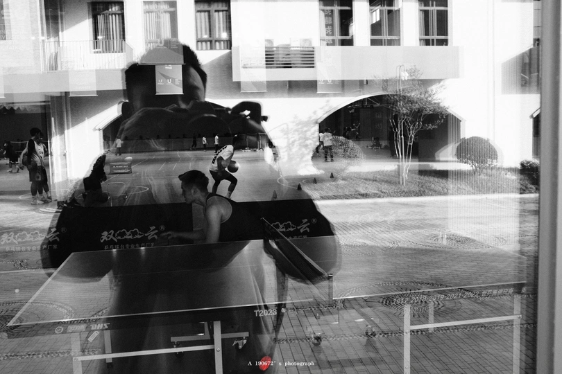 一张黑白照片 一个人拿着滑板 一个人拿着滑板 沿着建筑走