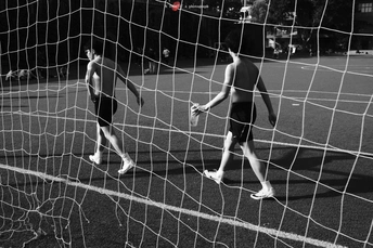 几个年轻男子在草地上踢足球 有球门和网。