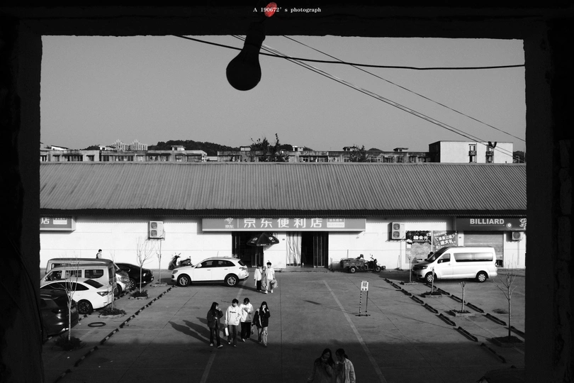 一张黑白照片 停车场 停着车 有人走动