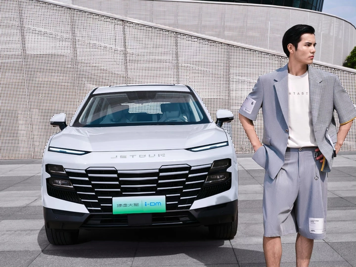 一个穿西装的男人站在一辆白色汽车旁边