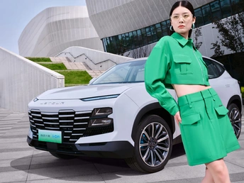 一位穿着绿色连衣裙和外套的女士走过街道上的一辆车