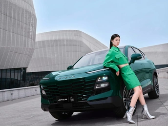 一位穿着绿色外套和高跟鞋的美女在现代建筑前与一辆绿色汽车合影。