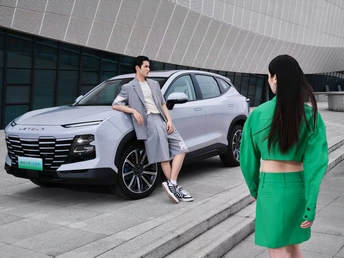 一位穿着绿色西装的男子站在一位穿着绿色西装的女子旁边 站在一辆汽车前。