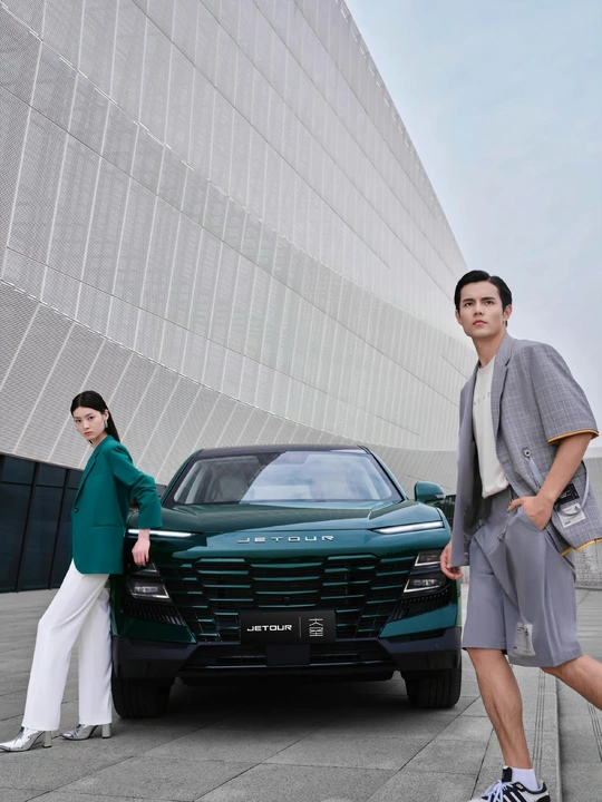 站在一辆绿色汽车旁边的一个男人 旁边站着一个正在摆姿势的女人。