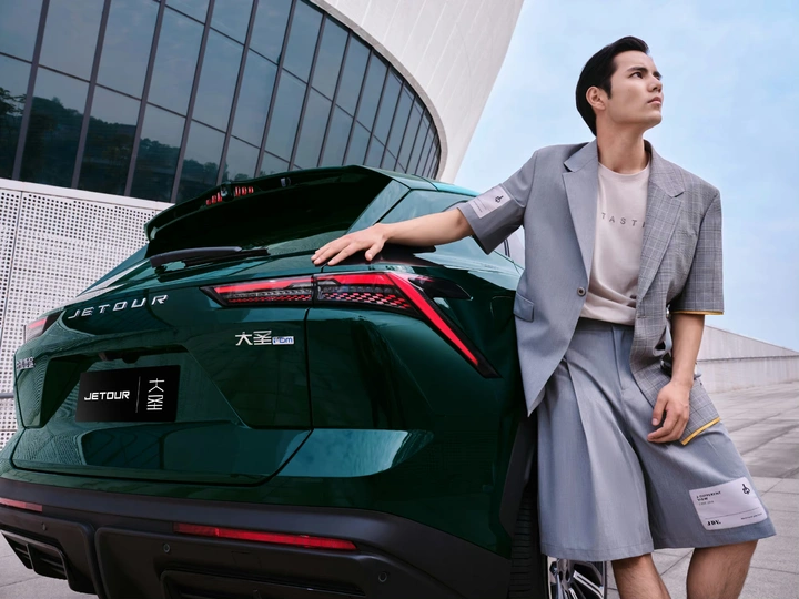 一位穿着商务套装的女性靠在一辆运动车上