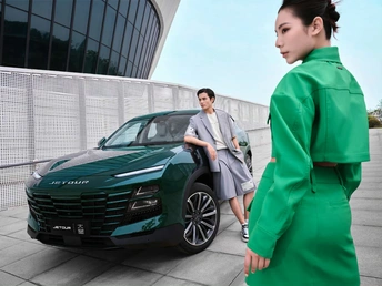 一位穿着绿色西装的女性站在一辆绿色汽车旁边