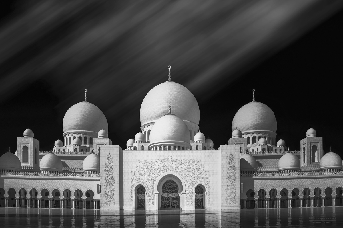 一张夜晚的黑白清真寺照片 带有发光的圆顶。