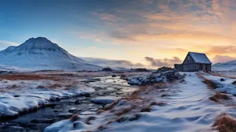 夕阳下的一个雪景 前景有老教堂和溪流 背景有山脉。