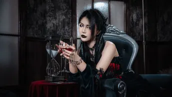 一位女性坐在桌子旁的一把椅子上 手里拿着一杯红葡萄酒。