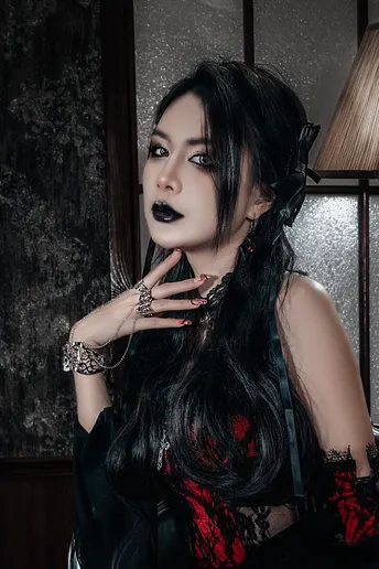 一个戴黑色头发的哥特女孩 涂着红唇 为画像摆姿势。