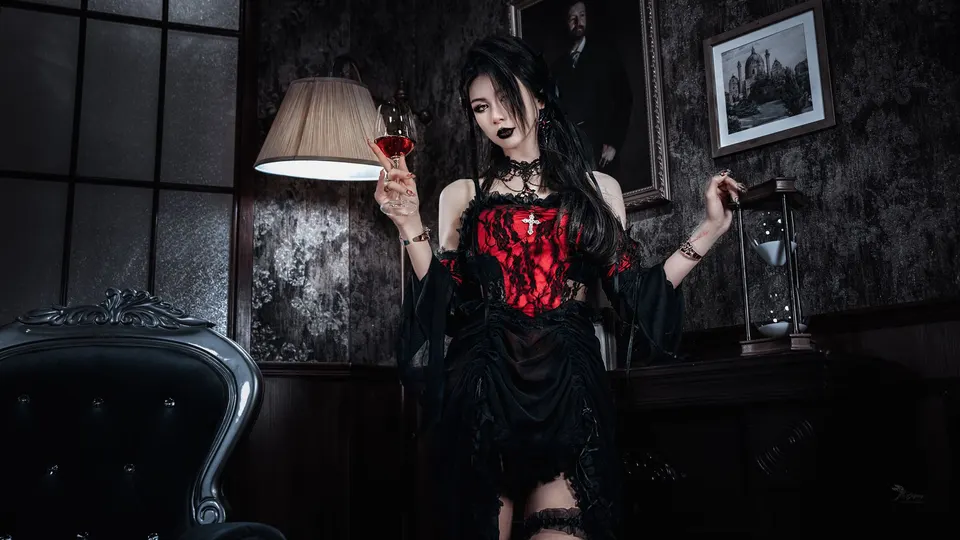 一个穿着黑色和红色连衣裙的女人手里拿着灯站在一个黑暗的房间里