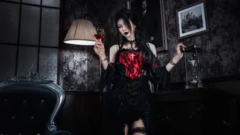 一个穿着黑色和红色连衣裙的女人手里拿着灯站在一个黑暗的房间里