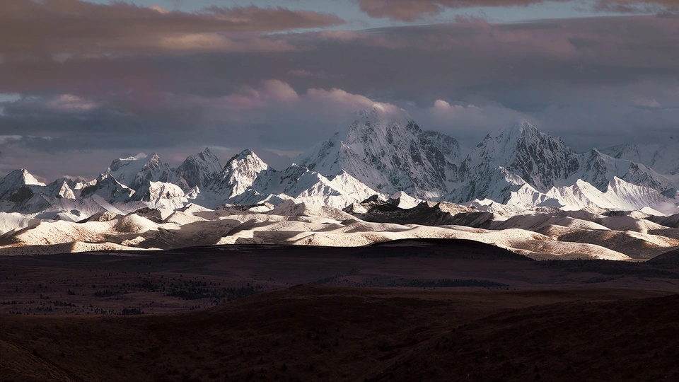 落日照耀着一座白雪皑皑的山脉