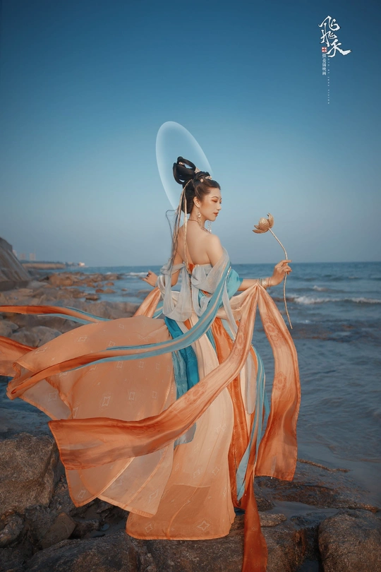 一位穿着连衣裙的美女站在海滩附近的水边