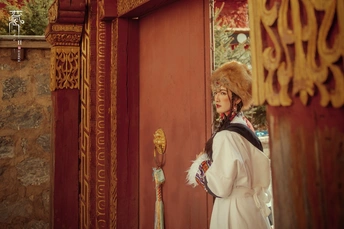 一位身着红袍和帽子站在神社前红门旁的女士