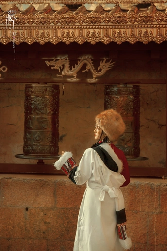 一位身着中国传统服装的女士 穿着白色长袍和帽子 站在一座寺庙前。