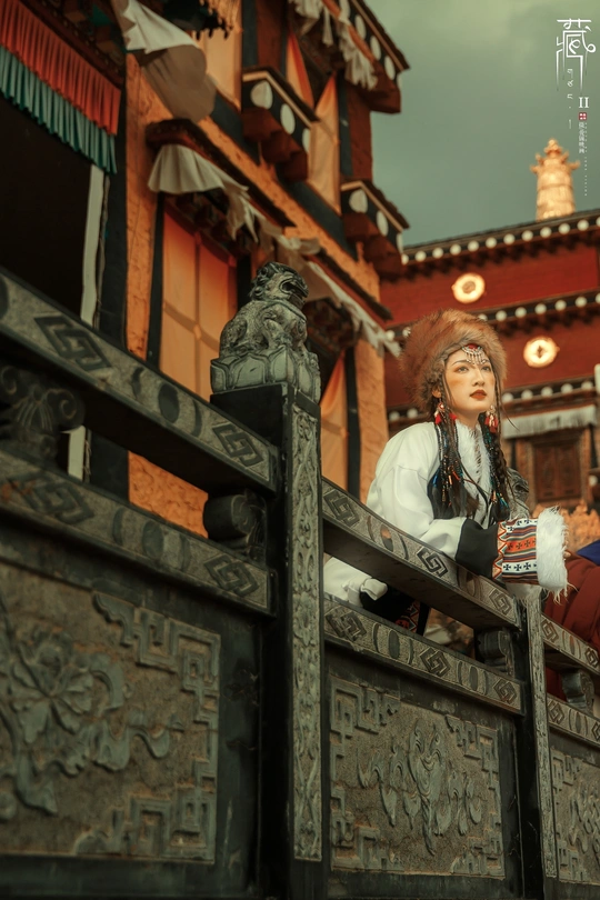 一些人在长栅栏附近的长椅上坐着 旁边有一栋建筑。