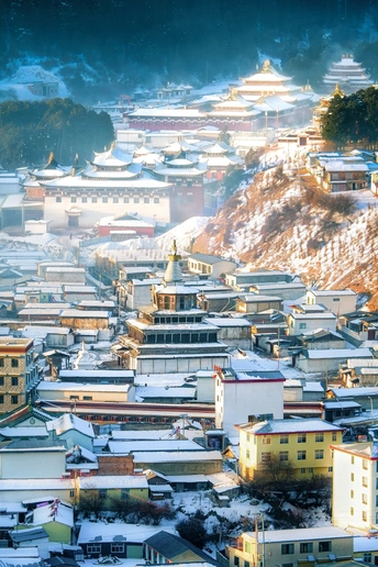 一个冬天的城市 建筑上有雪 背景是山脉。