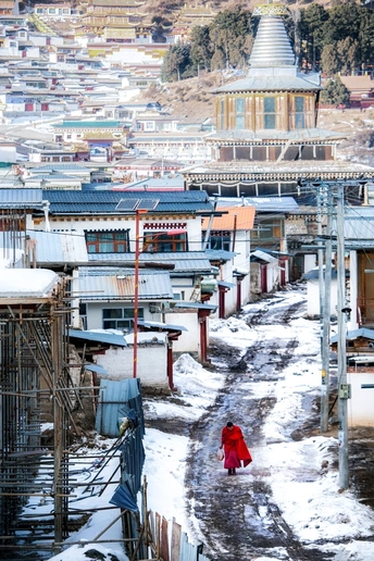 一个妇女和一个孩子在铺满雪的街道上行走 街道上飘着雪。