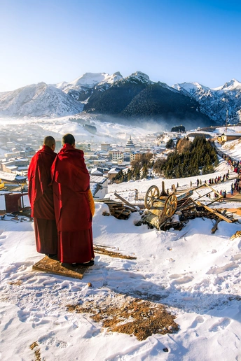 一些和尚站在雪中 眺望着一个被雪覆盖的小镇。