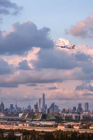 飞机在城市天际线上飞行 机场和建筑物在多云的天空下