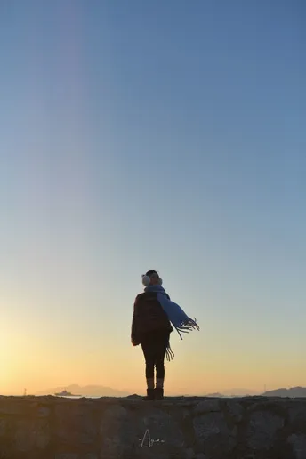 一个站在墙上的男人正在注视着一个站在岩石上观看日落的女人