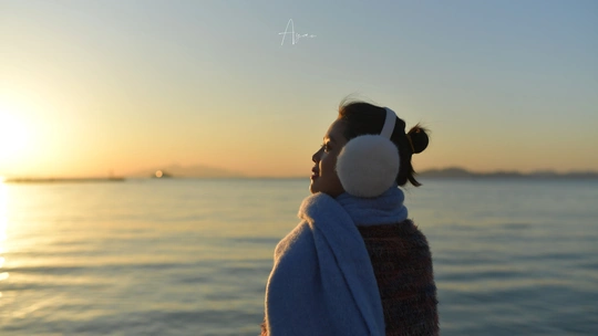 一位年轻女子裹着浴巾 凝视着海洋或海上的落日。