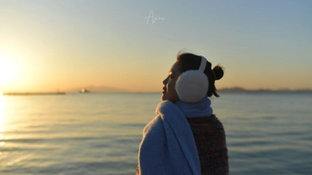 一位年轻女子裹着浴巾 凝视着海洋或海上的落日。