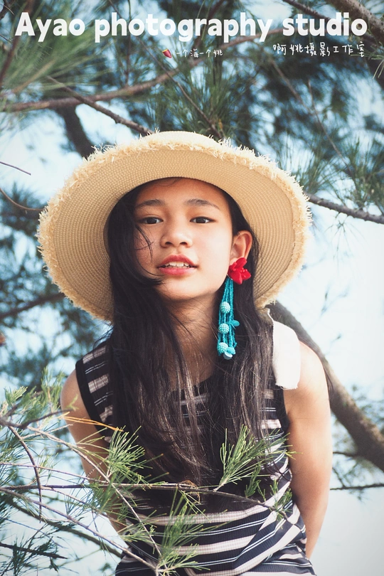 一位戴帽子的年轻女子站在一棵松树下面