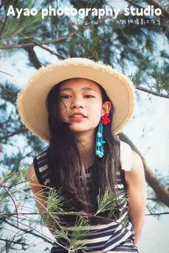 一位戴帽子的年轻女子站在一棵松树下面