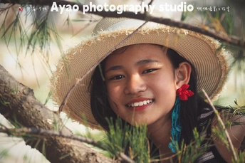 一位年轻女子戴着传统帽子坐在一棵松树上的肖像