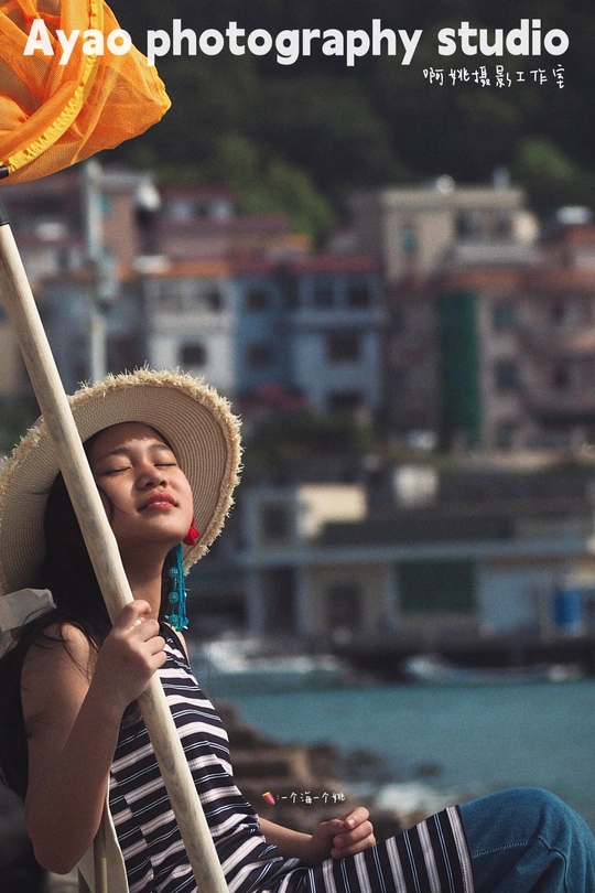 一位穿着条纹帽子 拿着雨伞 坐在有花的小船上的年轻女子