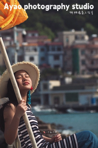 一位穿着条纹帽子 拿着雨伞 坐在有花的小船上的年轻女子