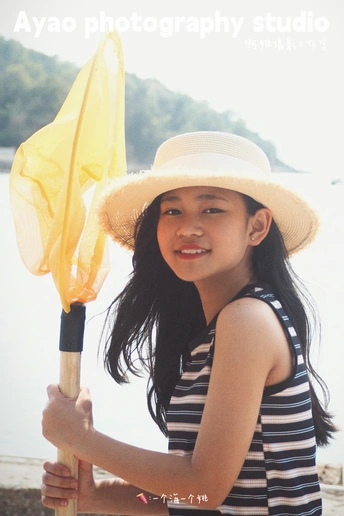 一位穿着条纹帽的小女孩拿着黄色雨伞