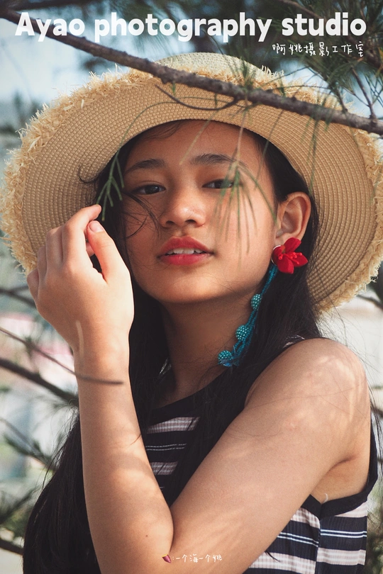 一位戴帽子的年轻女子在松树下面摆姿势