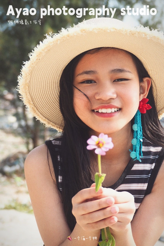 一个戴帽子的小女孩拿着一朵小花