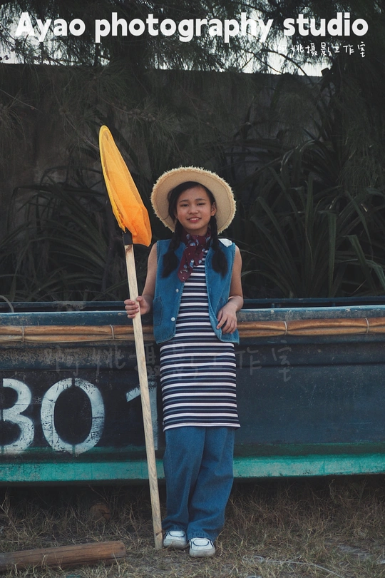 一位戴帽子拿着桨站在船边的年轻女子