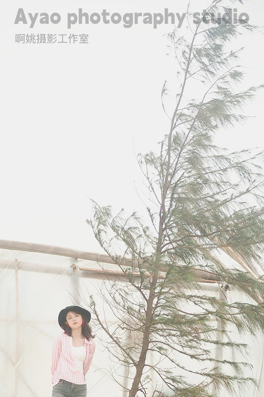 一位年轻女子戴着黑色帽子站在一匹马和一棵树旁边