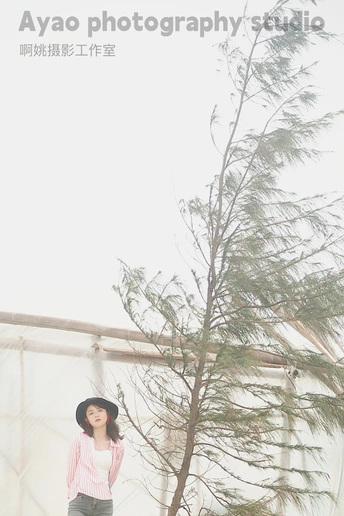 一位年轻女子戴着黑色帽子站在一匹马和一棵树旁边