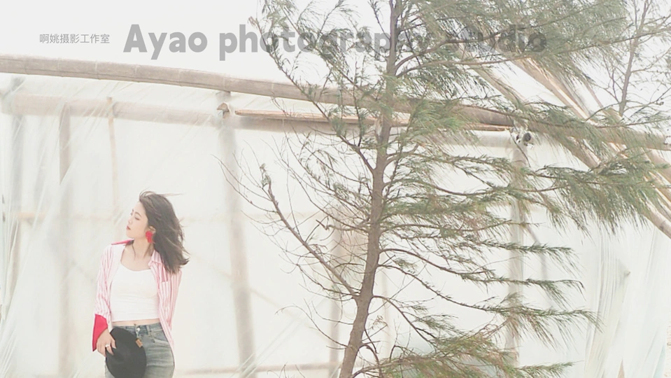 一位年轻女子站在一棵树旁 站在一把伞下