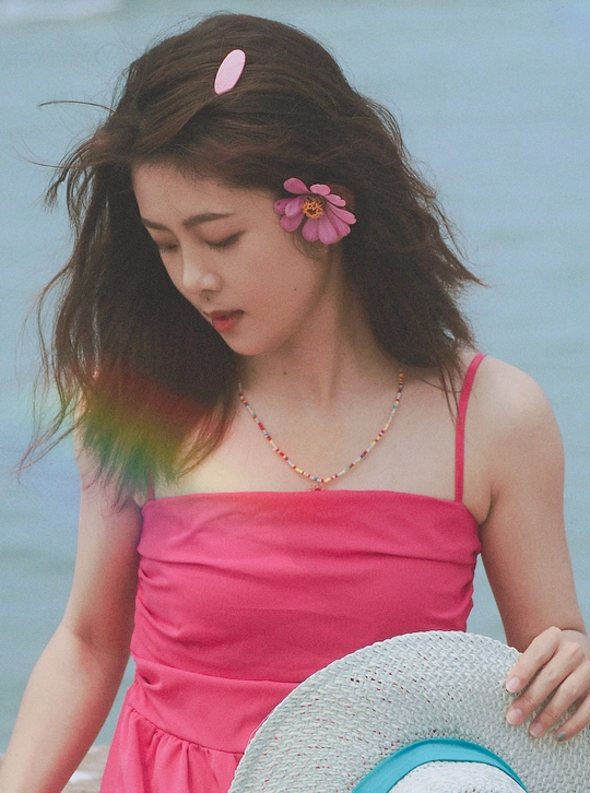 一位穿着粉红色连衣裙 头戴蓝色花帽子的年轻女子