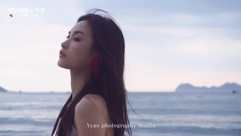 一位长发年轻女子站在海滩上 眺望着远方的大海。