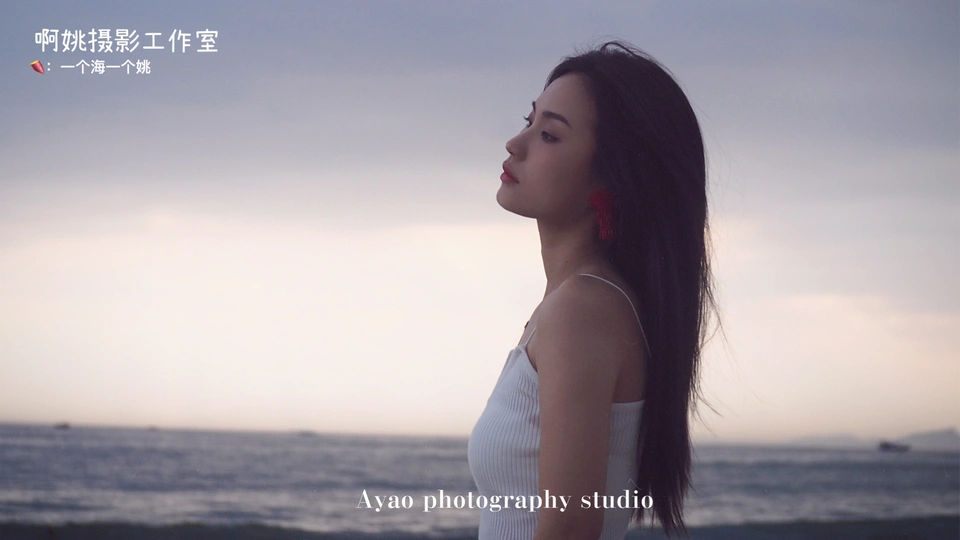 一位穿着白色连衣裙站在海滩上的女人 背景是海洋和天空。