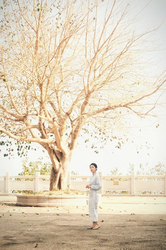 一位年轻男孩和一位妇女站在街角下的一棵树下。