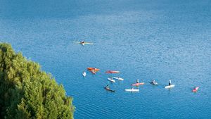 人们在划艇上漂浮在平静的蓝色水域中。